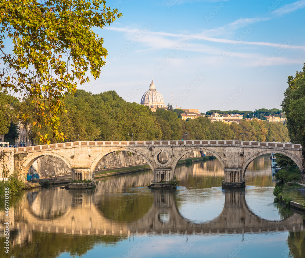 Bridge on Tiber river in Rome, Italy. Vatican Basilica cupola in background with sunrise light.