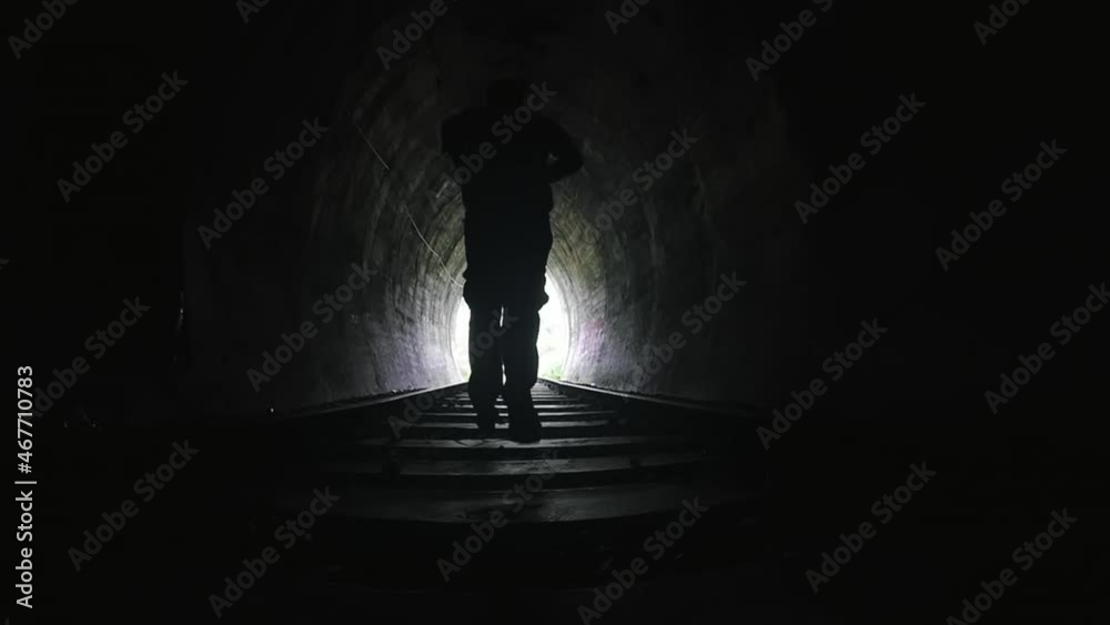 Slow motion video of man running in dark spooky tunnel toward bright light at end of passage way. Freedom and hope concept video background