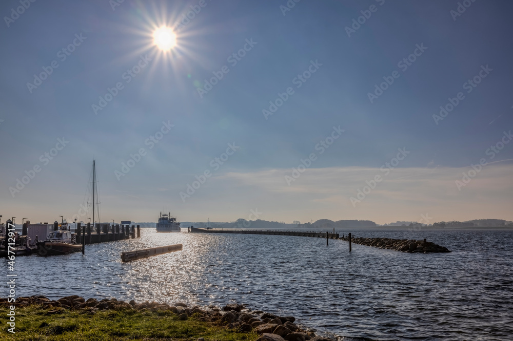 Raddampfer fährt in den sonnenbestrahlten Hafen von Maasholm im Oktober 2021