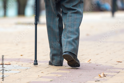Legs of an elderly man walking with a cane on the street