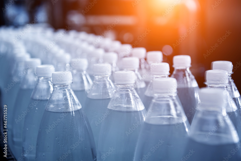 Conveyor belt with bottles of drinking water at a modern beverage plant. Conveyor belt with bottles of drinking water at a modern beverage plant.