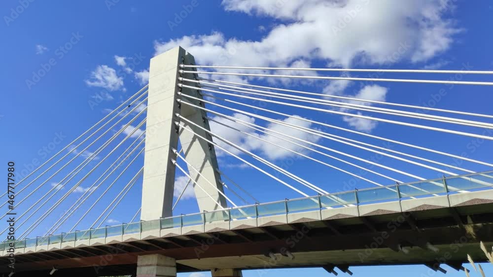 Modern bridge over the river on the background of blue sky with white clouds Modern bridge over the river on the background of blue sky with white clouds