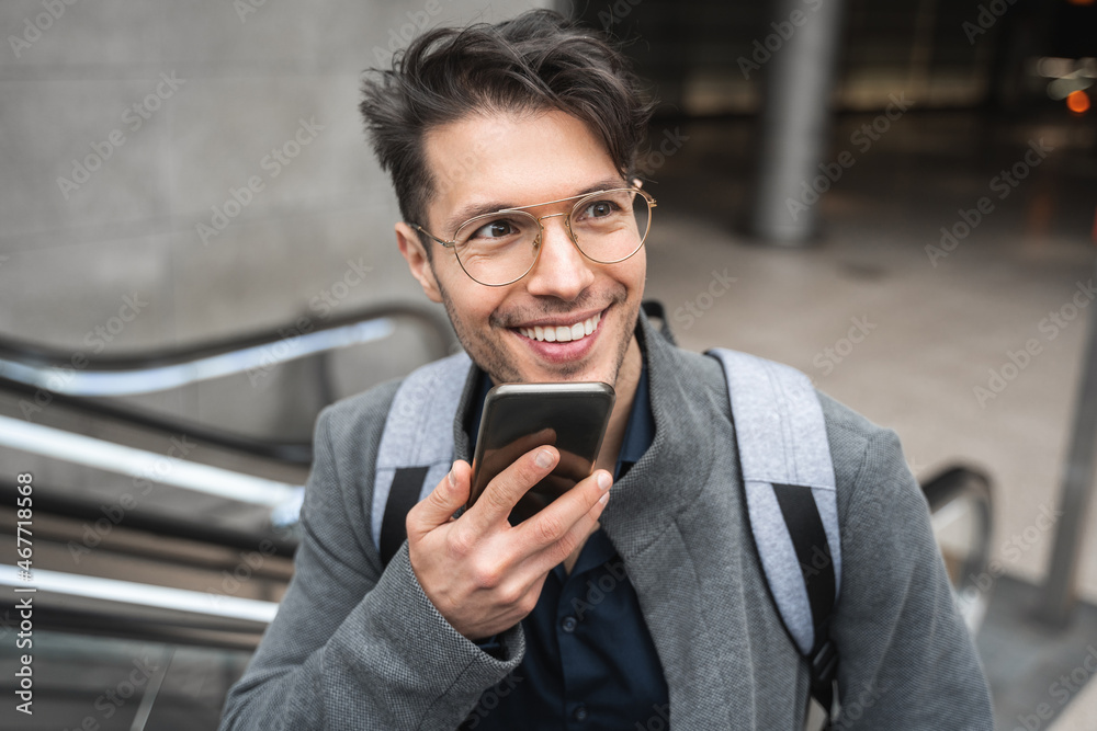 Man recording voice message via smartphone while going at moving staircase to the airport Man recording voice message via smartphone while going at moving staircase to the airport