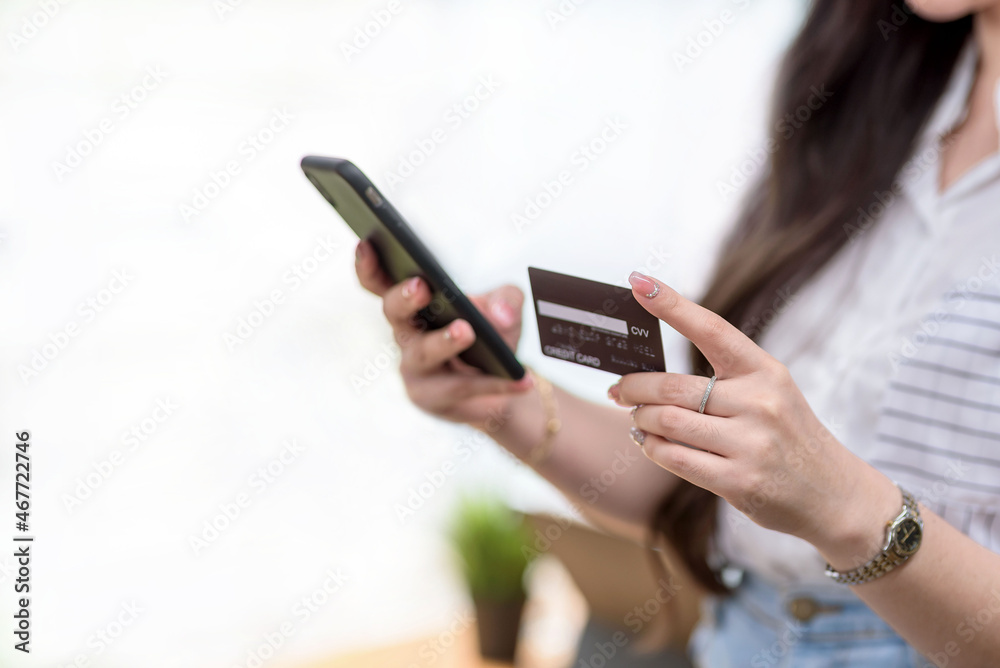 Close up. woman hands holding smartphone and using credit card for online shopping.