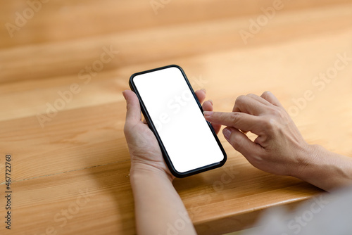 Close-up of a businesswoman hand holding a smartphone blank white screen enjoy social media applications ads. Mock up.