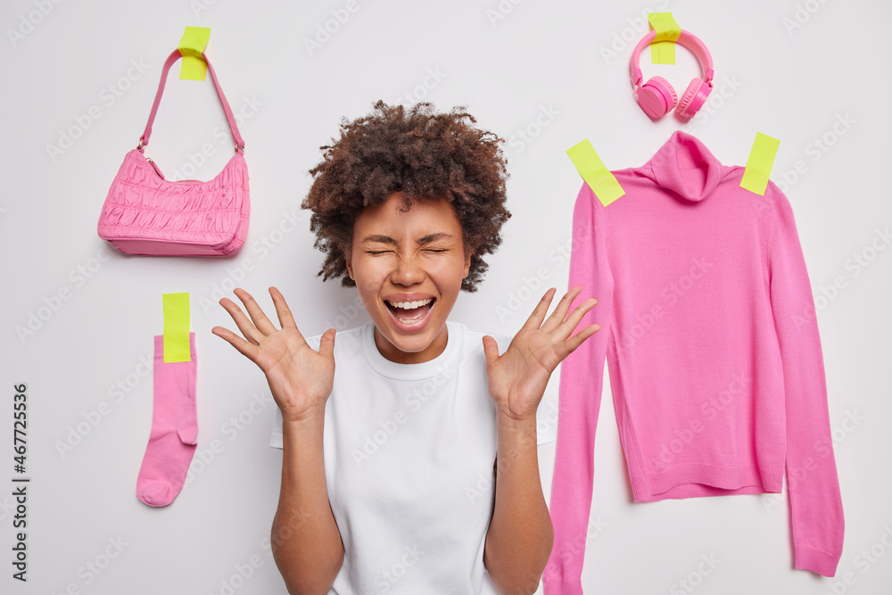 Positive woman exclaims loudly keeps palms raised reacts on something ...