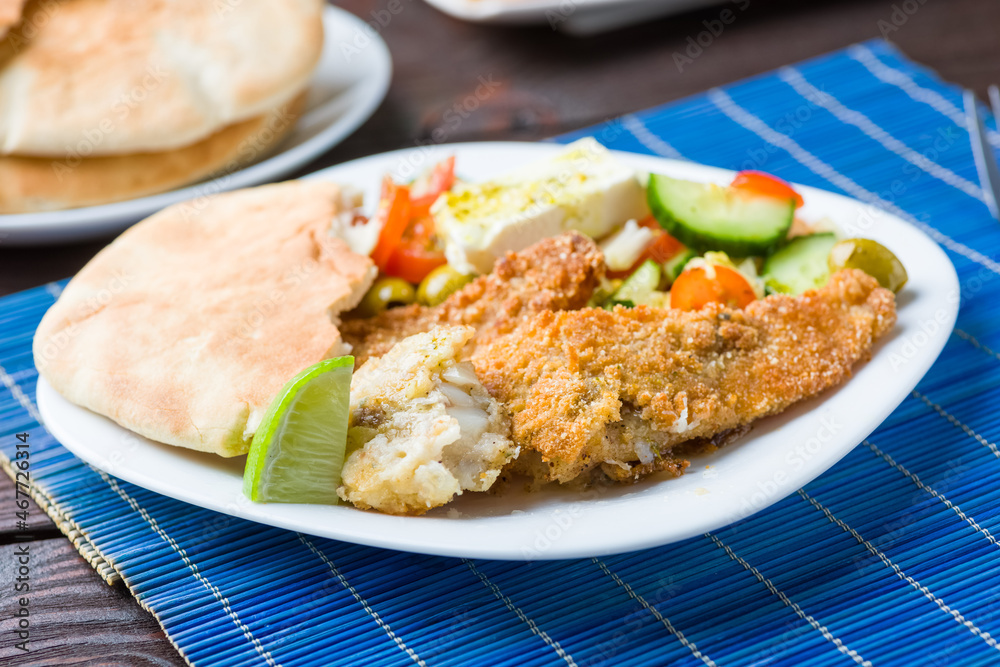 Baked fish served with vegetable salad with feta cheese Baked fish served with vegetable salad with feta cheese