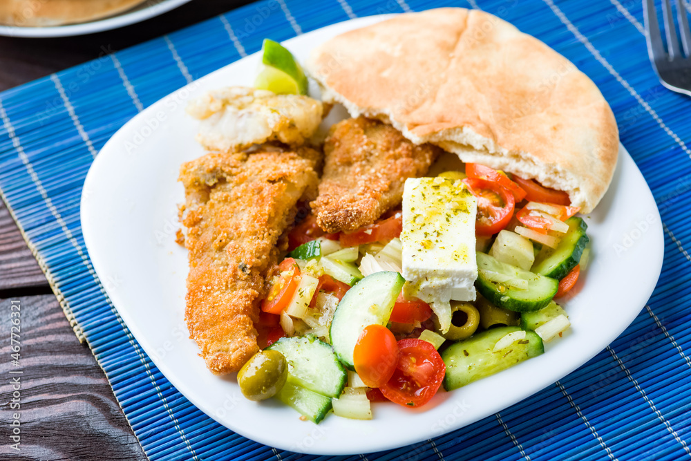 Baked fish served with vegetable salad with feta cheese Baked fish served with vegetable salad with feta cheese