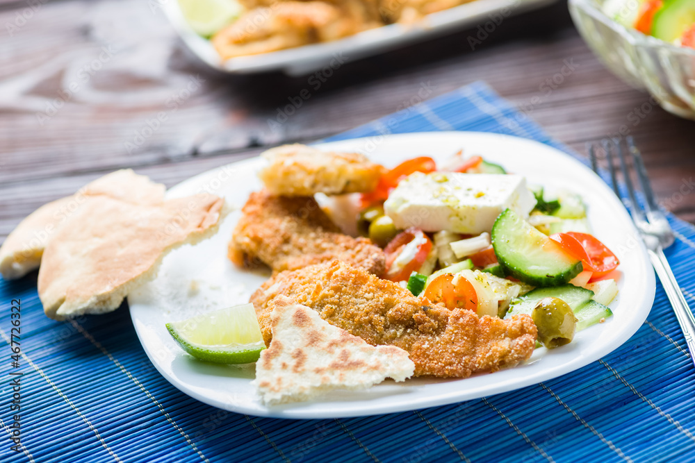 Baked fish served with vegetable salad with feta cheese Baked fish served with vegetable salad with feta cheese