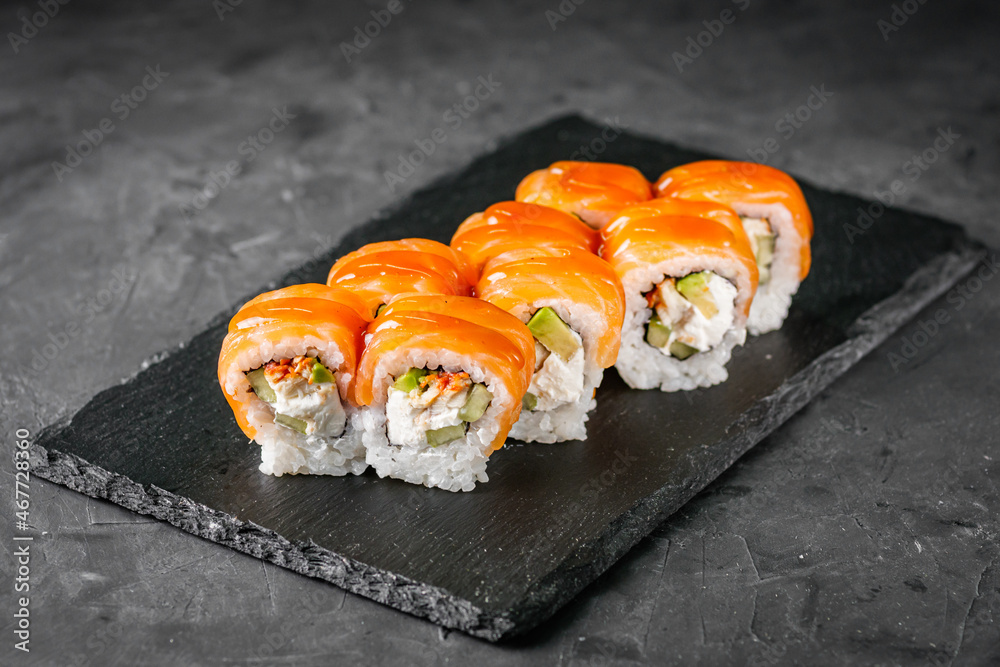 appetizing sushi roll philadelphia with avocado cheese eel cucumber and salmon on a black stone plate appetizing sushi roll philadelphia with avocado cheese eel cucumber and salmon on a black stone plate
