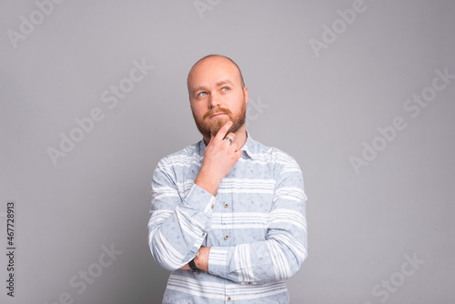 Young man with beard in casual making thinking gesture over grey background