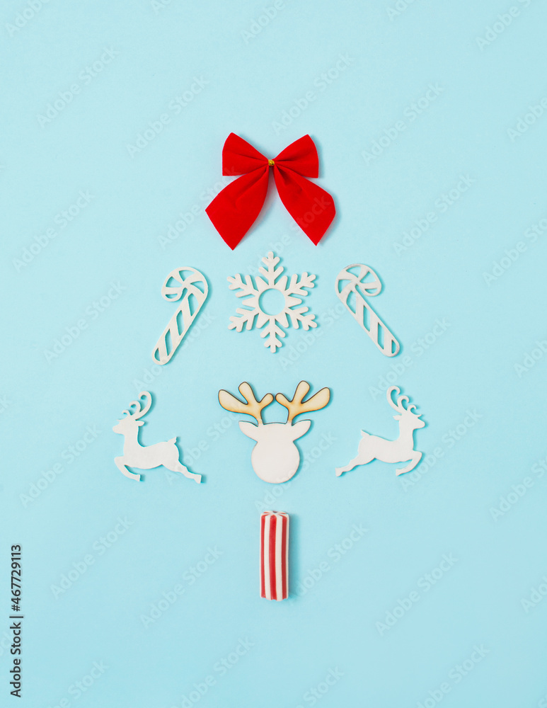 Christmas tree made with snowflake, ribbon, dear horns and candies on bright pastel blue background. Flat lay. Copy space. Minimal trendy creative composition.