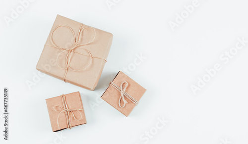 Three craft gift boxes with jute thread lie on the left against a white background .