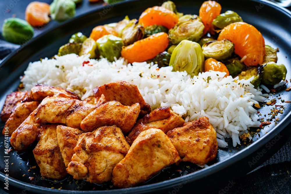 Fried chicken nuggets with white rice, brussels sprouts, carrots and tangerines on wooden table
Fried chicken nuggets with white rice, brussels sprouts, carrots and tangerines on wooden table