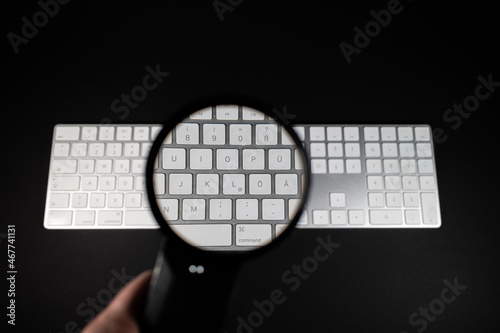  magnifying glass enlarges the middle part of a white keyboard
