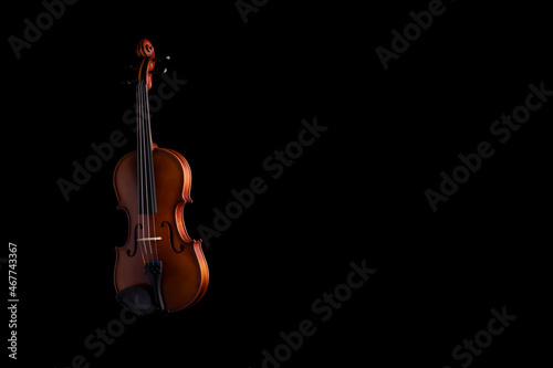 A violin or viola with four strings with a beautiful soft light hitting it on a black background. No.19