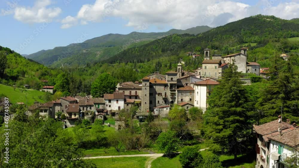 Aerial Shot Of Built Residential Structures On Hills, Drone Flying Over Green Landscape In Sunlight - Apennine Mountains, Italy