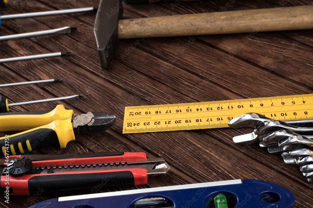 Locksmith's working tool. Mechanical assembly and disassembly tool. Screwdrivers, pliers, wire cutters, building level, tape measure, hammer, wrenches, square and other tools on a wooden surface. Locksmith's working tool. Mechanical assembly and disassembly tool. Screwdrivers, pliers, wire cutters, building level, tape measure, hammer, wrenches, square and other tools on a wooden surface.