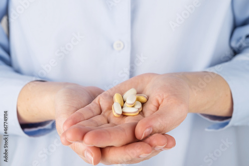 A woman holds a handful of pills in her hands, close-up.