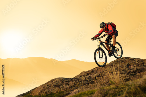 Fototapeta Naklejka Na Ścianę i Meble -  Cyclist Riding Bike on the Rocky Trail in the Summer Mountains at Sunset. Extreme Sport and Enduro Cycling Concept.