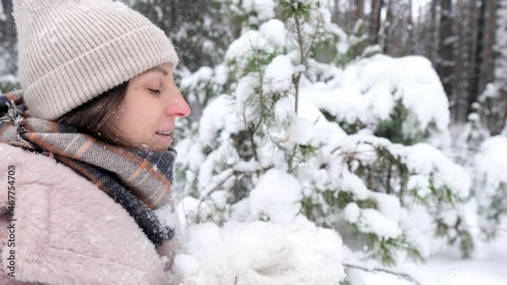 Beautiful young woman blow snow from her palms. Girl standing among the winter forest and playing with snow on a sunny day. Beautiful young woman blow snow from her palms. Girl standing among the winter forest and playing with snow on a sunny day.