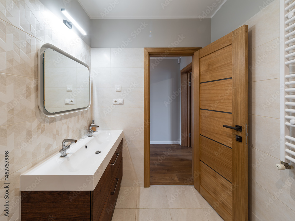 Modern interior of bathroom. White sink. Wooden door with tile floor. Modern interior of bathroom. White sink. Wooden door with tile floor.