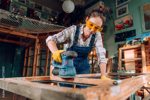 Young woman wearing protective glasses working in the workshop photo