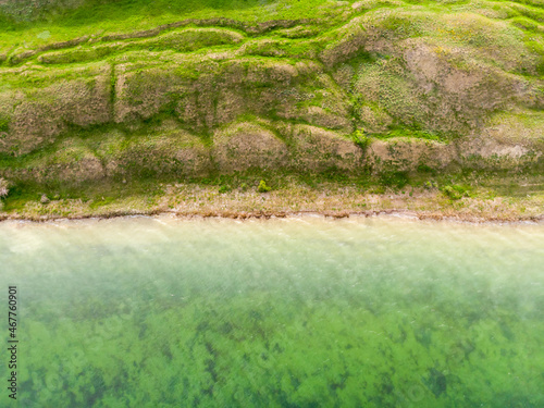 Top down aerial view of surrealistic landscape near calm green water