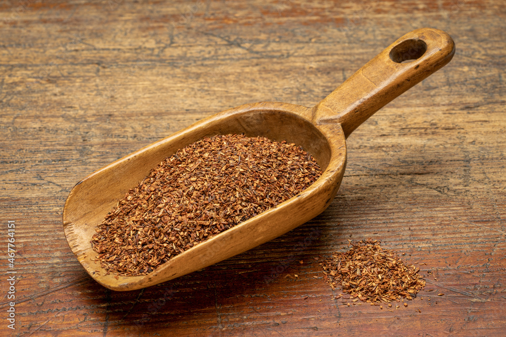 rooibos tea, made from the South African red bush, naturally caffeine free - vintage wooden scoop on rustic, weathered wood rooibos tea, made from the South African red bush, naturally caffeine free - vintage wooden scoop on rustic, weathered wood