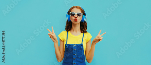 Portrait of cool girl with headphones listening to music on a colorful blue background
