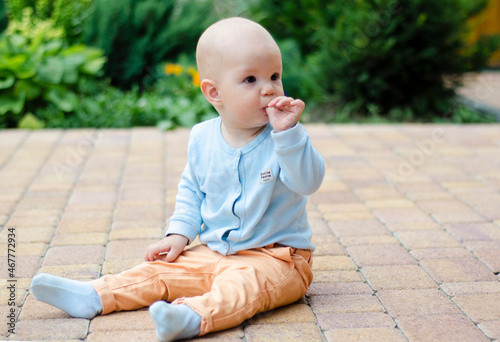 A little happy baby sitting on the chair at the restaurant and chewing his finger. Covering with hip seat. Focus on mouth. Selective focus.