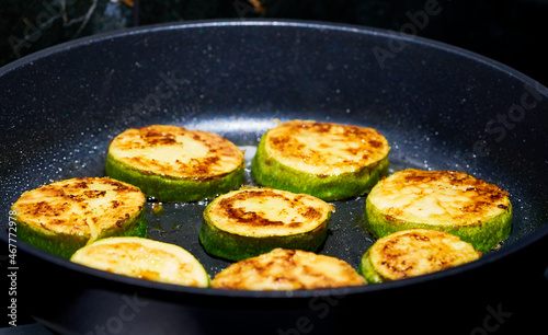zucchini are fried in a skillet in the kitchen