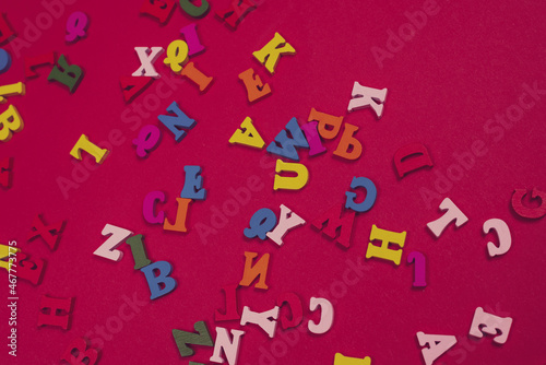 Random colorful alphabet on a red background, colorful letters.
