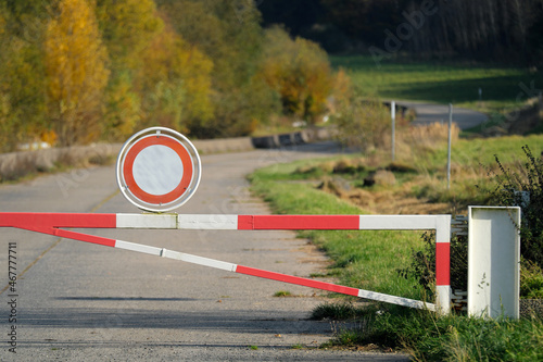 Rot-weiße Schranken mit Verkehrszeichen Durchfahrt verboten auf Panzerstraße von Truppenübungsplatz an der Grenze zu Naturschutzgebiet - Stockfoto