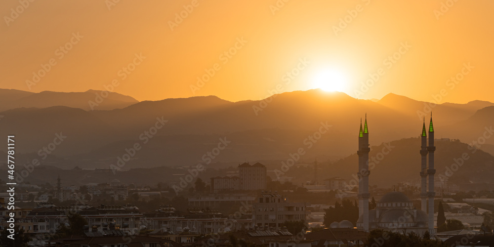 Sunrise over the mountains with mosque and Turkish city at the foreground