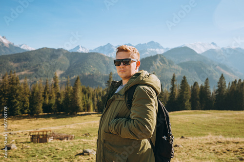 Young man in sunglasses see view on top mountain. Freedom, happiness, travel and vacations concept, outdoor activities © mdyn