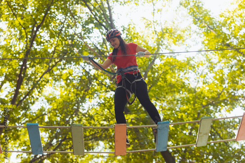 The woman is doing exercise in the adventure rope park