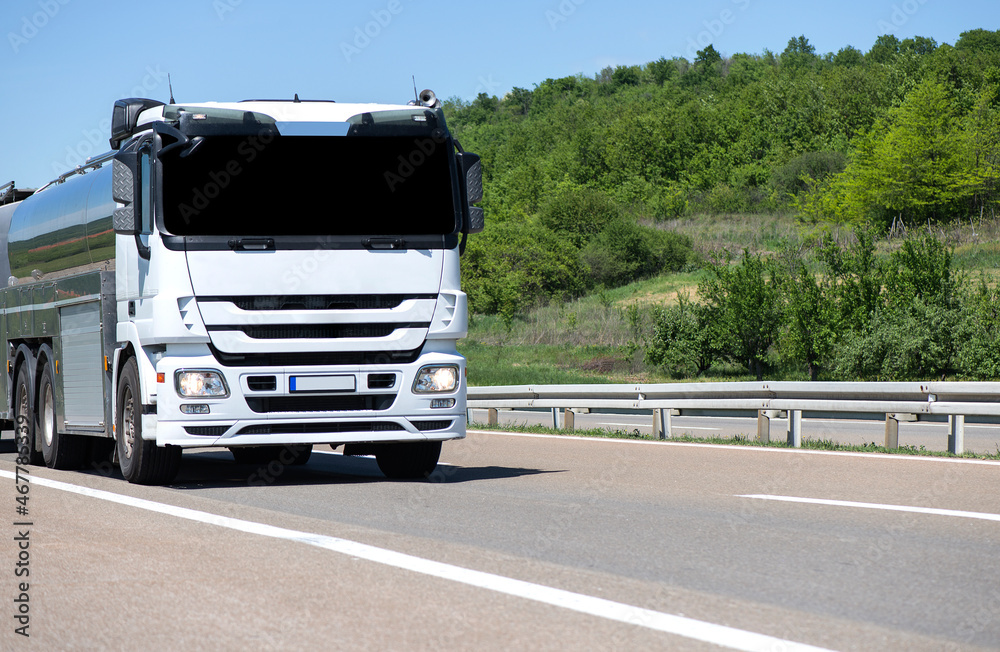 Isothermal Tank truck driving on highway. Oil and Gas Transportation and Logistics. Metal chrome cistern tanker with petrochemicals products. Liquid Chemical Freight. Soft focus possible granularity