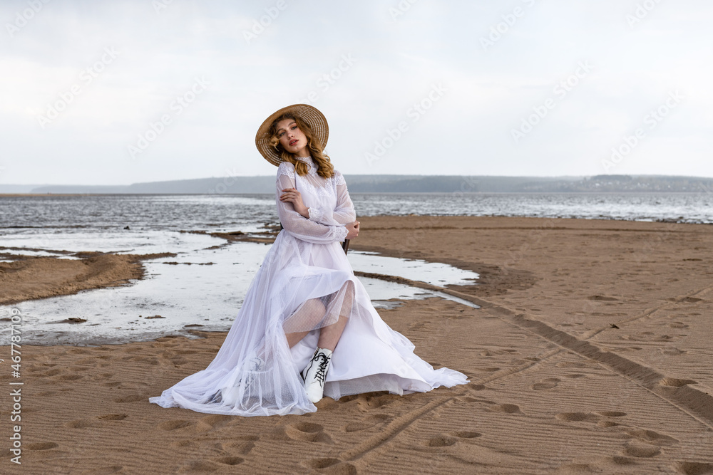 Happy young girl in a white dress on the river bank. Stormy sky in the clouds Happy young girl in a white dress on the river bank. Stormy sky in the clouds