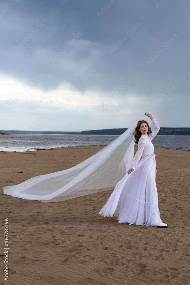 Happy young girl in a white dress on the river bank. Stormy sky in the clouds Happy young girl in a white dress on the river bank. Stormy sky in the clouds