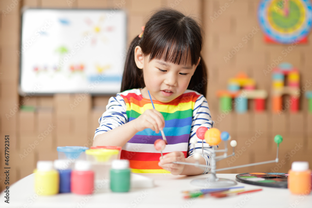 young girl painting swivelling solar system toy at home young girl painting swivelling solar system toy at home