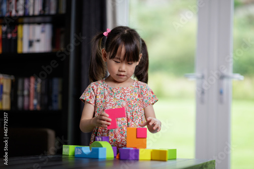 young girl playing toy blocks at home
