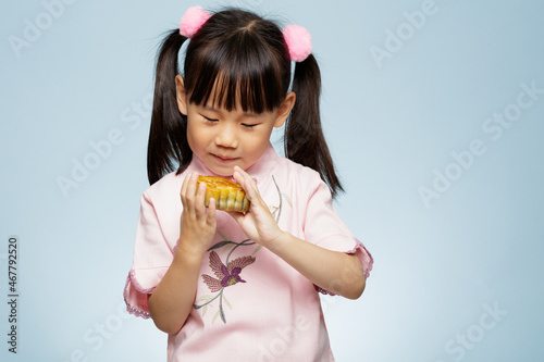 Photography young girl holding traditional  Chinese moon cake against plain blue background