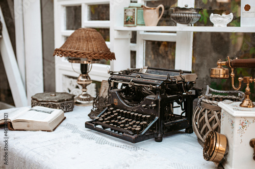 Vintage old fashioned typewriter machine on wooden desk next to window in light white shabby chic vintage french Provence country cottage interior room with antique objects 
 photo