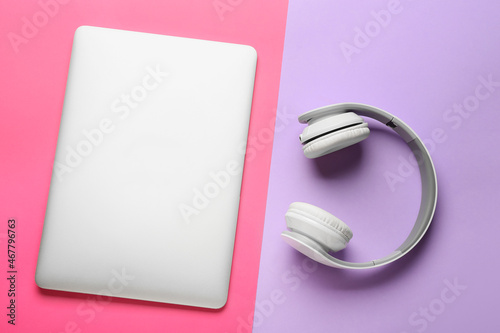 Modern laptop and headphones on color background