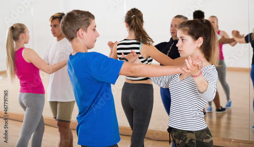 Teen boys and girls having dancing partner dance in classroom