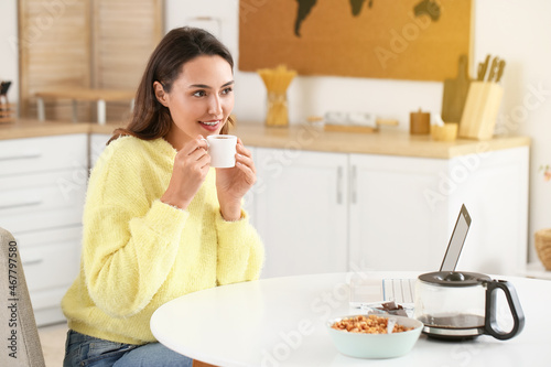 Morning of beautiful woman with laptop drinking coffee at home