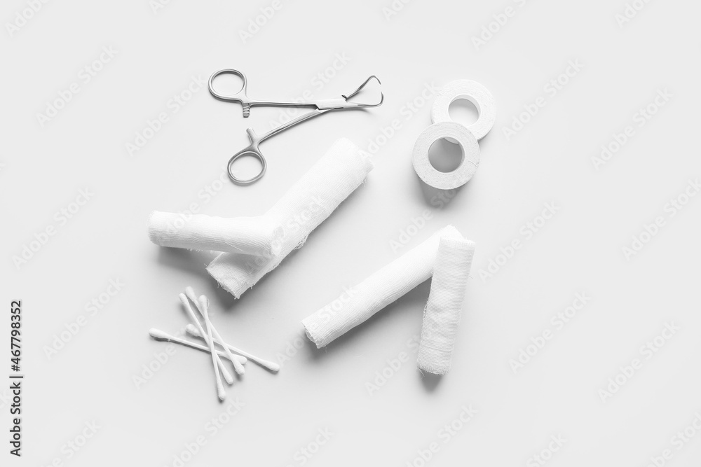 Surgical tool, bandage rolls, medical plaster and cotton buds on light background Surgical tool, bandage rolls, medical plaster and cotton buds on light background