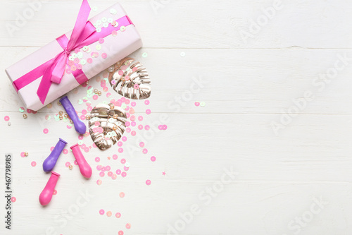 Beautiful balloons and gift on light wooden background
