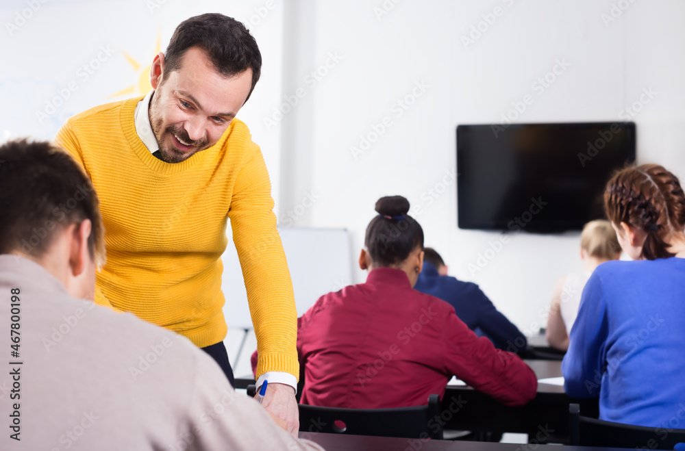 Obraz premium Teacher explaining a difficult problem to student during test in the class